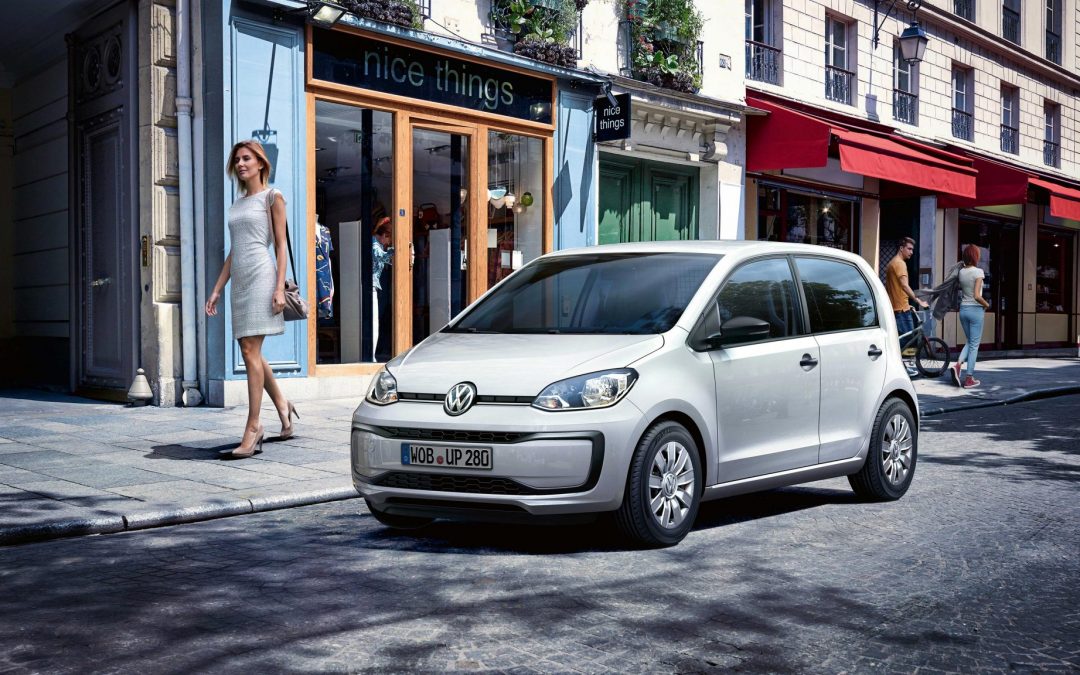 Photograph of a Volkswagen up! parked on a street outside a row of shops